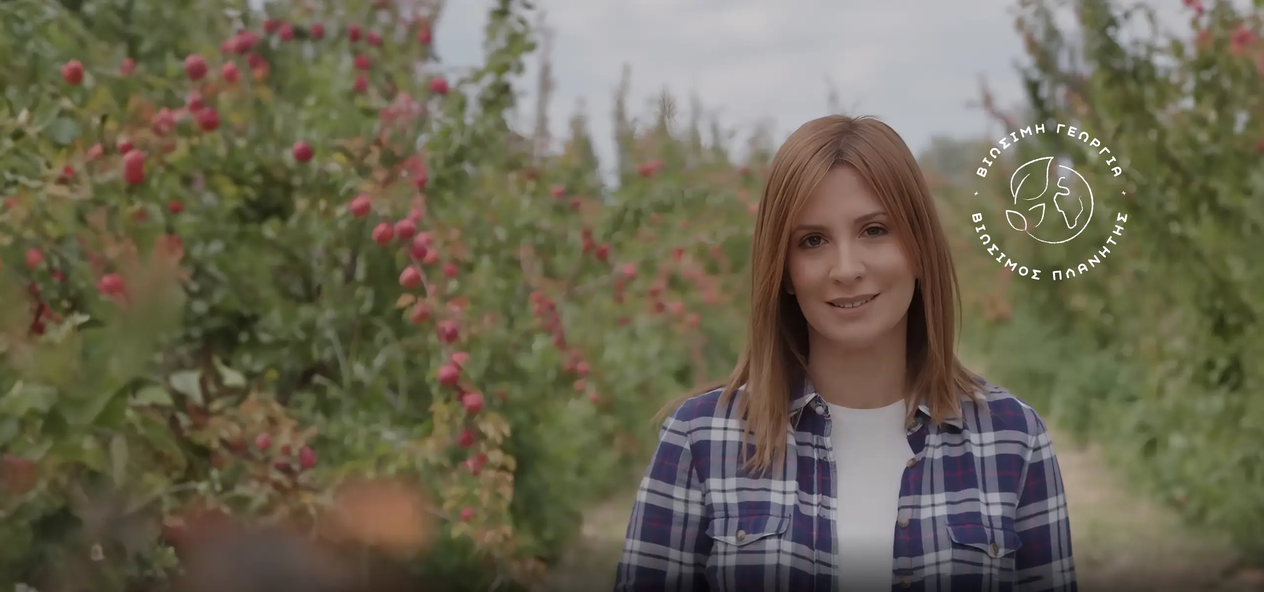 Person standing in field with red plants and trees background
