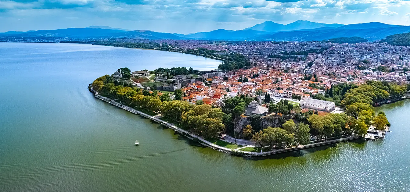 Εναέρια άποψη των Ιωαννίνων με τη λίμνη Παμβώτιδα, αστικό ιστό και ορεινό τοπίο στο βάθος